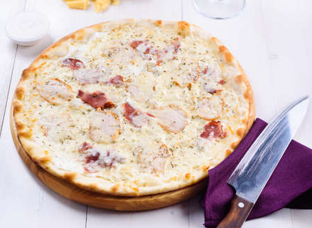 Fresh cheese pizza with ham and cream sauce on white plate, close up. Italian traditional cuisine, copy space. Foodの写真素材