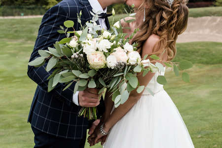 Happy bride and groom holding hands and kiss on wedding ceremony outdoors, copy space.の写真素材