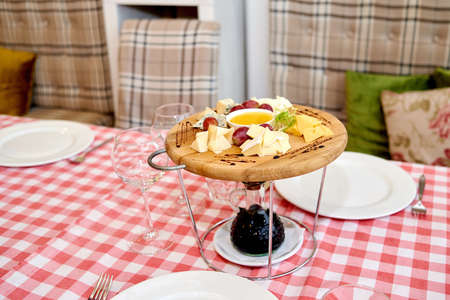 Wooden board with assortment of delicious cheese, grapes and honey on dinner table.の写真素材