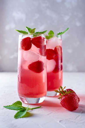 Strawberry lemonade, cocktail with ice and mint in glass on gray stone concrete table background, copy space.の写真素材