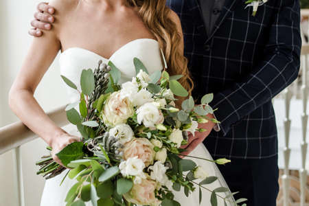 Happy bride and groom hugging at wedding day indoors, copy space. Wedding couple in love, newlyweds. Groom holding the bride's waist. Wedding conceptの写真素材