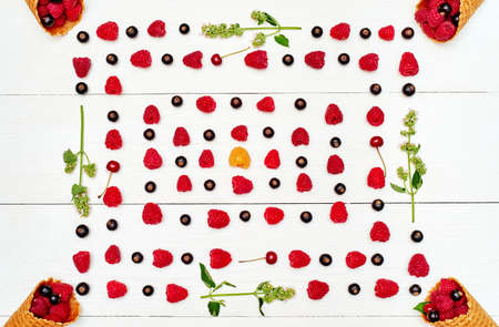 Top view of frame from sweet fresh organic raspberries, black currants and cherries in waffle cone,...
