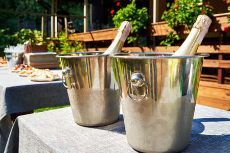 Bottle of cold champagne in bucket with ice on table for wedding reception outdoors, copy space.の写真素材