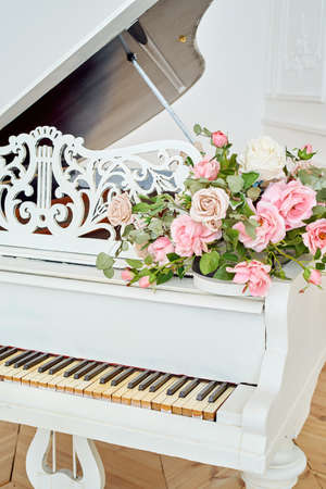 White grand piano with rose flowers in white classic interior, copy spaceの写真素材