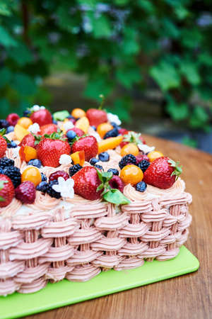Delicious birthday or wedding cake with fresh fruits and berries on board outdoors, copy space. Cake decorated with strawberry, raspberry, blackberry, blueberry, apricot and peachの写真素材