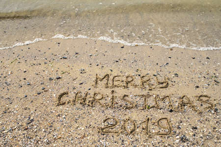 Merry Christmas 2019 written on tropical beach sand, copy space. Holiday concept, top viewの写真素材