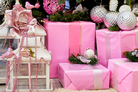 Christmas background with pink gift boxes decorated with ribbon and fir branches on floor under Christmas tree, copy space. Winter holidays conceptの写真素材