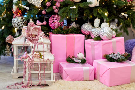 Christmas background with pink gift boxes decorated with ribbon and fir branches on floor under Christmas tree, copy space. Winter holidays conceptの写真素材