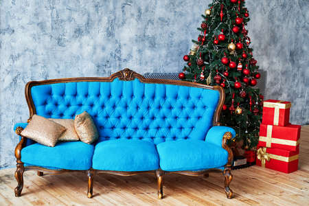 Christmas morning, copy space. Classic apartments with blue buttoned sofa, decorated fir tree and...