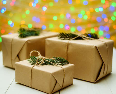 Christmas background with gift boxes wrapped in kraft paper with fir tree branch on golden blured,...