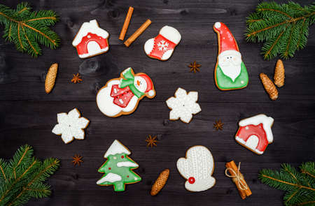 Christmas background with homemade gingerbread cookies and fir tree branches on wooden table, top view, flat lay. Fir tree, snowflake, house, santa, mitten, sock, cinnamon. Christmas food, copy spaceの写真素材