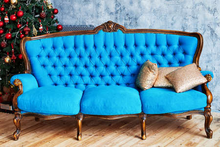Christmas morning, copy space. Classic apartments with blue buttoned sofa, decorated fir tree and...