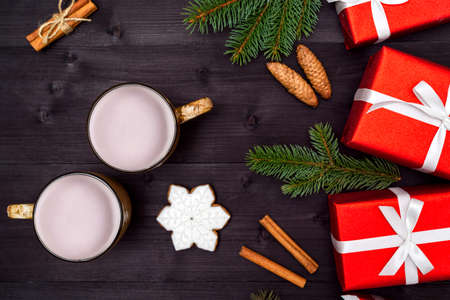 Top view of two cups of hot cocoa, ginger snowflake cookie, red gift boxes and fir tree branches on wooden background, copy space. Christmas background, free space. Flat lay, above, overheadの写真素材