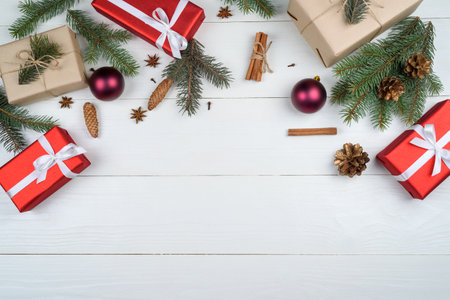 Christmas background with gift boxes, fir tree branches, pine cones, cinnamon sticks and stars anise on white wooden background, free space. Holiday greeting card, copy space. Flat lay, top viewの写真素材