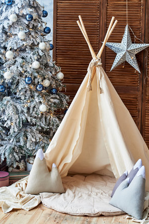Christmas tree with gifts and wigwam in child room, copy space. Childen room interior with decorated play tipi tent. Scandinavian styleの写真素材