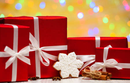 Christmas background with red gift boxes with white ribbon bow, snowflake cookie and cinnamon sticks on golden blured, sparkling background, copy space. Holiday greeting cardの写真素材
