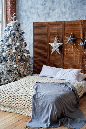 Christmas decorated bedroom interior with comfortable bed, Christmas fir tree and stars on wooden wall, copy space. Cozy home moment. Happy New Year. Christmas morningの写真素材