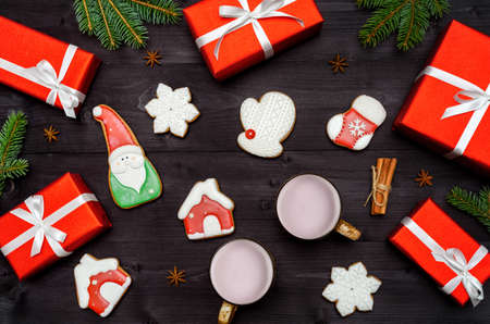 Christmas gingerbread cookies, two cups of hot cocoa, red gift boxes, fir tree branches on dark wooden background, copy space. Top view, flat lay. Santa, snowflake, mitten, house, stockingの写真素材