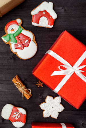 Christmas gingerbread cookies, red gift boxes, cinnamon and anise star on dark wooden background, copy space. Top view, flat lay. Snowflake, house, snowman, stocking. Holiday conceptの写真素材