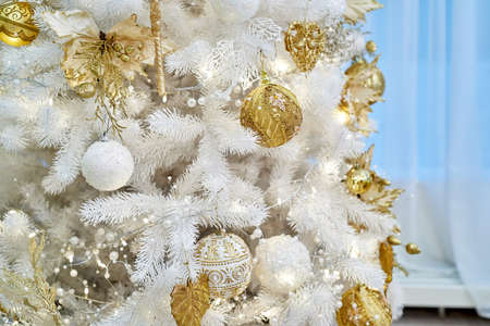 Closeup of decorated Christmas tree white and golden baubles and garland on blue background, copy space. Christmas decorations. Holiday background. Greeting cardの写真素材
