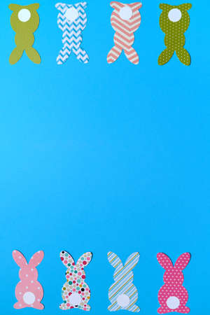 Easter bunny decoration on blue background, copy space. DIY holiday handicraft of colorful rabbits. Flat lay, top view. Happy Easter conceptの写真素材