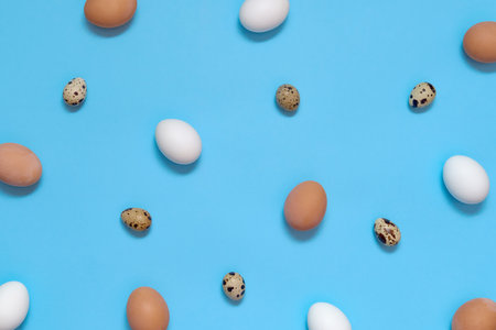 Creative Easter background with white and brown eggs on blue paper, copy space. Top view, flat lay. Easter eggsの写真素材