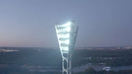 Switching on the light tower of a football stadium against a sunset and a night city cinematic smooth movement of a droneの写真素材
