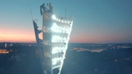 Switching on the light tower of a football stadium against a sunset and a night city cinematic smooth movement of a droneの写真素材