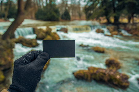 blank business card for your text and logo on the background of the Austrian mountain lake. black blank business card. black sheet of cardboard in hand and free standingの写真素材