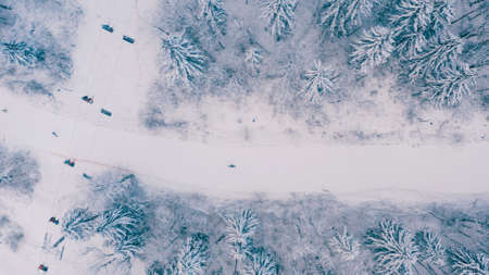 Aerial view of snowy snowboarder ride alone on a narrow mountain track, ski slopes in the forested...