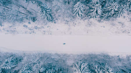 Aerial view of snowy snowboarder ride alone on a narrow mountain track, ski slopes in the forested area in mountains. Top view of tracks near trees and ski resort in winter season in 4Kの写真素材
