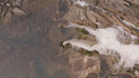 Waterfall in the Winter. Rapid Flow of Water from a Mountain Creek and Stone Rapids with Snow. The...