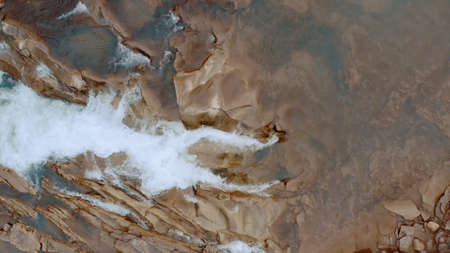 Waterfall in the Winter. Rapid Flow of Water from a Mountain Creek and Stone Rapids with Snow. The river Prut in Ukrainian Carpathians in Yaremche city.Melting ice and snow on the river in the forest.の写真素材