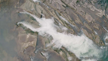 Waterfall in the Winter. Rapid Flow of Water from a Mountain Creek and Stone Rapids with Snow. The river Prut in Ukrainian Carpathians in Yaremche city.Melting ice and snow on the river in the forest.の写真素材