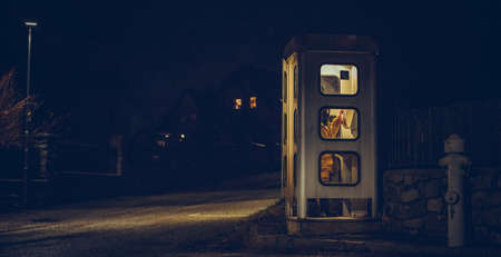 the girl speaks in the night telephone booth. mystical and mysterious street phone. dangerous place...