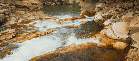 Waterfall in the Winter. Rapid Flow of Water from a Mountain Creek and Stone Rapids with Snow. The...