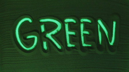 Hand drawing the Word Green in the Green Sand. Male hand writes the word on the sand with green backlight. Top view 4k resolutionの写真素材