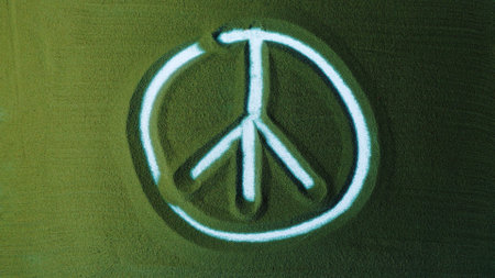 Hand drawing the Pacific peace symbol in the Green Sand and then erases it. Male hand writes peace symbol on the green sand with white backlight. Top view 4k resolutionの写真素材
