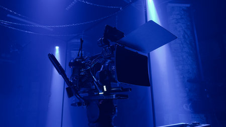 Professional film camera setup in a dark studio with dramatic blue light. Cinematic atmosphere capturing the creative process and visual storytelling of modern film production.の写真素材