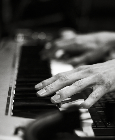 The hands of a man playing the piano. Black and white photo.
