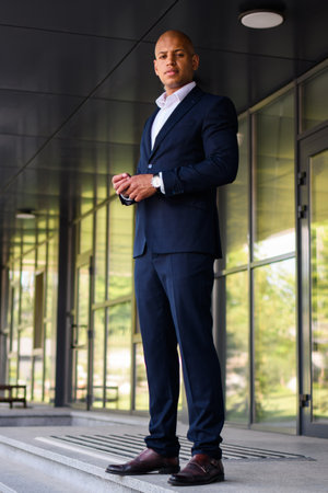 Hairless african american businessman in formal wear looking at camera near office outdoorsの写真素材