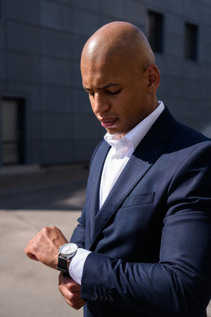 African american businessman looking at wristwatch on street