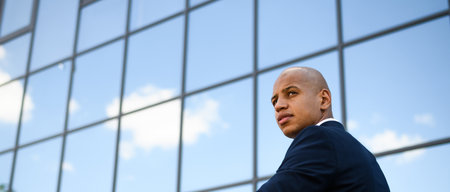 Hairless african american businessman looking away near building, banner shotの写真素材