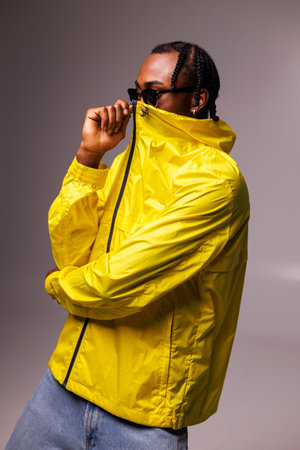 Trendy african american man in sunglasses and jeans zip up bright windbreaker jacket isolated on...