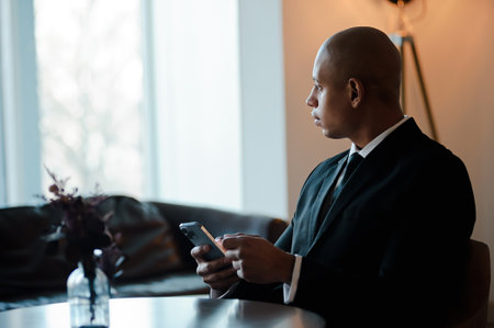 African american businessman in suit using smartphone in lobby of business center