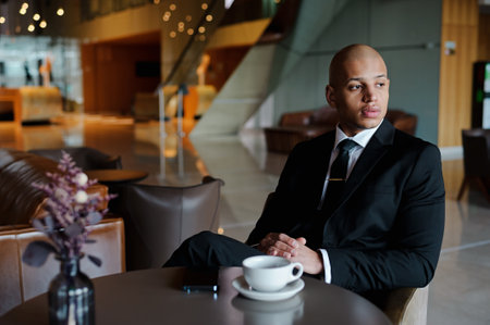 African american businessman waiting near coffee and smartphone in the lobby of business center