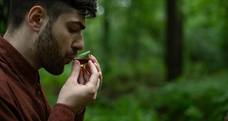 Side view of young man drinking shu puer in summer forest