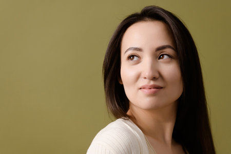 Portrait of brunette Asian woman looking away isolated on greenの写真素材