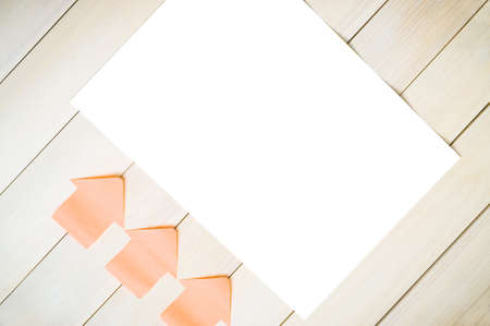 Stickers in form of arrows on the wooden background pointing at a white sheet.White sheet.Sticker arrows.Background of boards.の写真素材