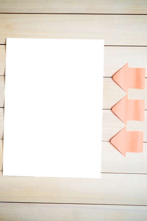 Stickers in form of arrows on the wooden background pointing at a white sheet.White sheet.Sticker arrows.Background of boards.の写真素材